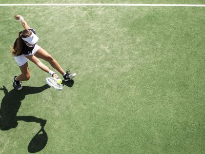 En kvinde der slår til en tennisbold set oppefra