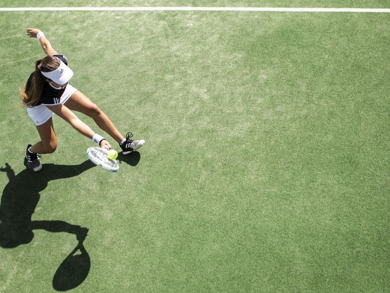 En kvinde der slår til en tennisbold set oppefra