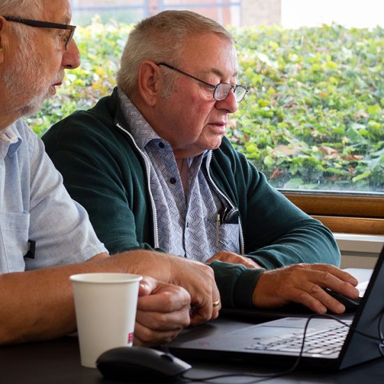 En frivillig i bibliotekets IT-café hjælper en borger ved en bærbar pc