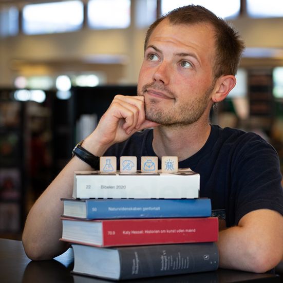 Bibliotekets litteraturformidler Stinus bag en stak bøger
