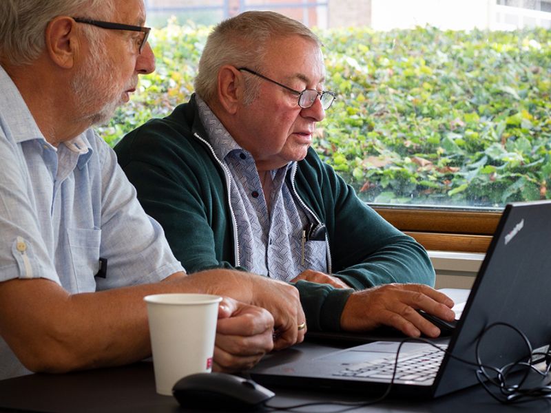 En frivillig i bibliotekets IT-café hjælper en borger ved en bærbar pc