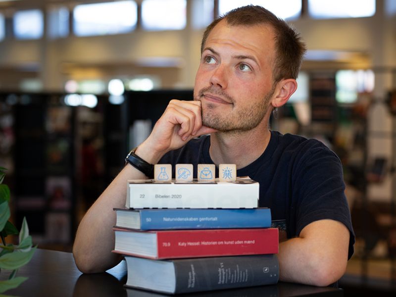Bibliotekets litteraturformidler Stinus bag en stak bøger